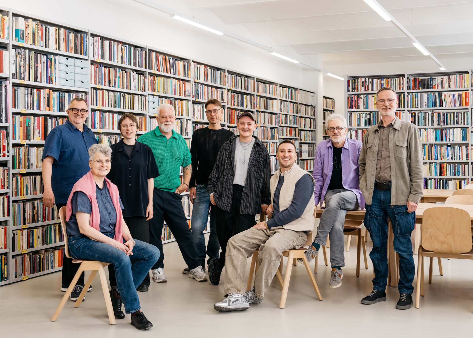 Gruppe von zehn Personen posiert in einer Bibliothek vor Bücherregalen.