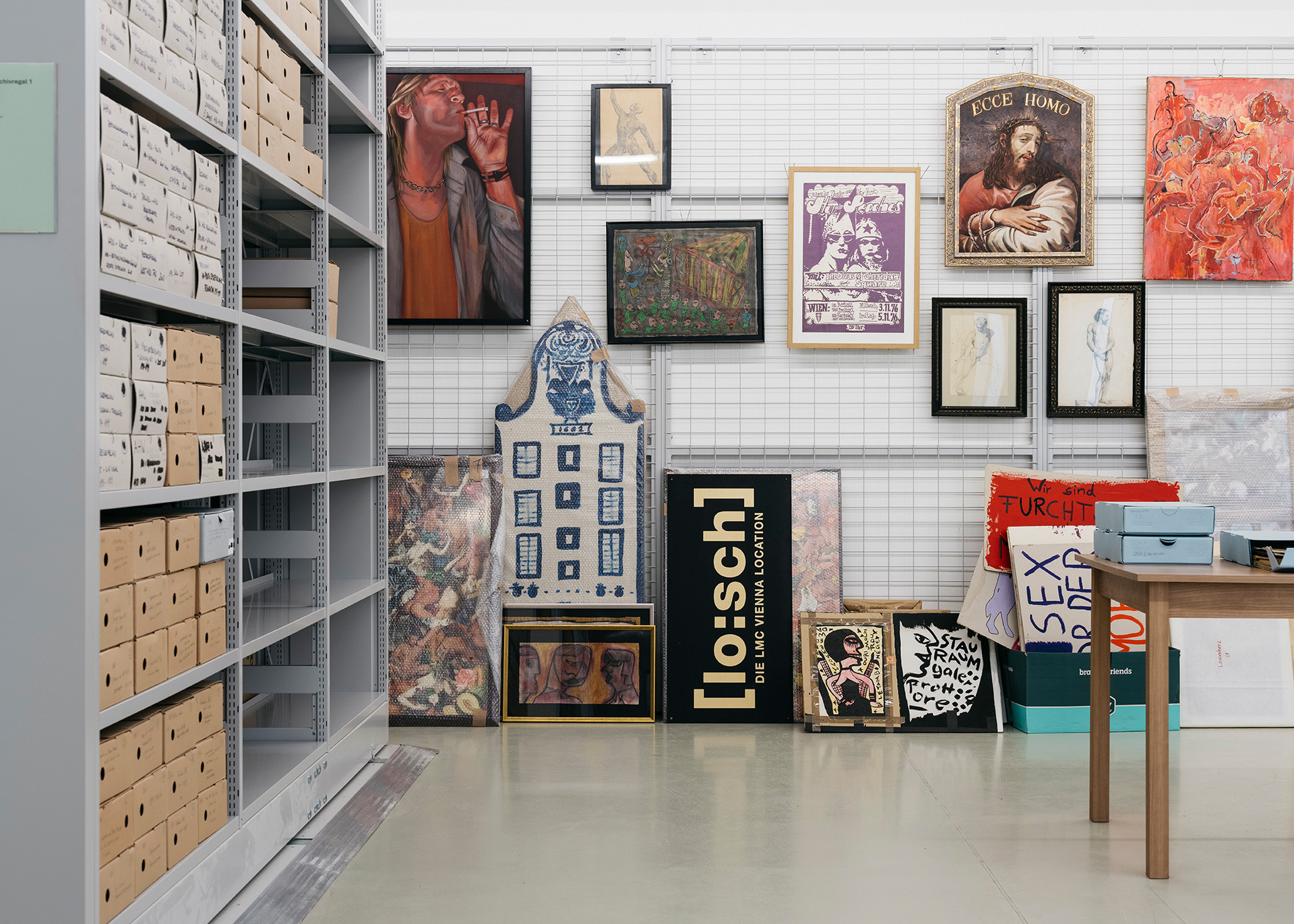 Kunstwerke und Archivboxen in einem modernen Ausstellungsraum, vielfältige Stile und Farben.