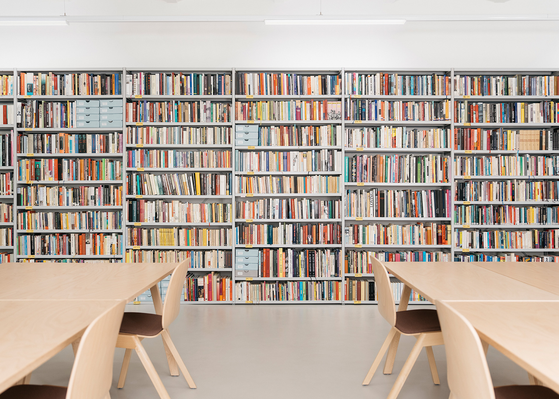 Moderne Bibliothek mit Regalen voller Bücher und mehreren Tischen zum Lesen und Arbeiten.