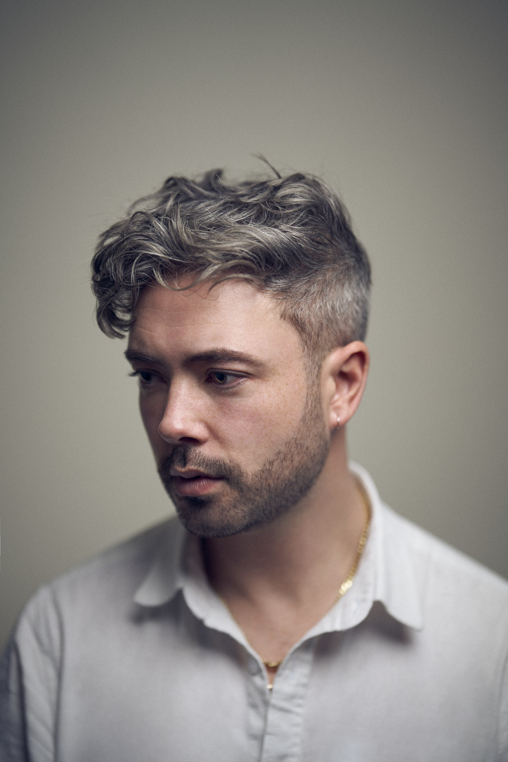 Porträt einer Person mit grauem Haar, die nachdenklich zur Seite schaut.