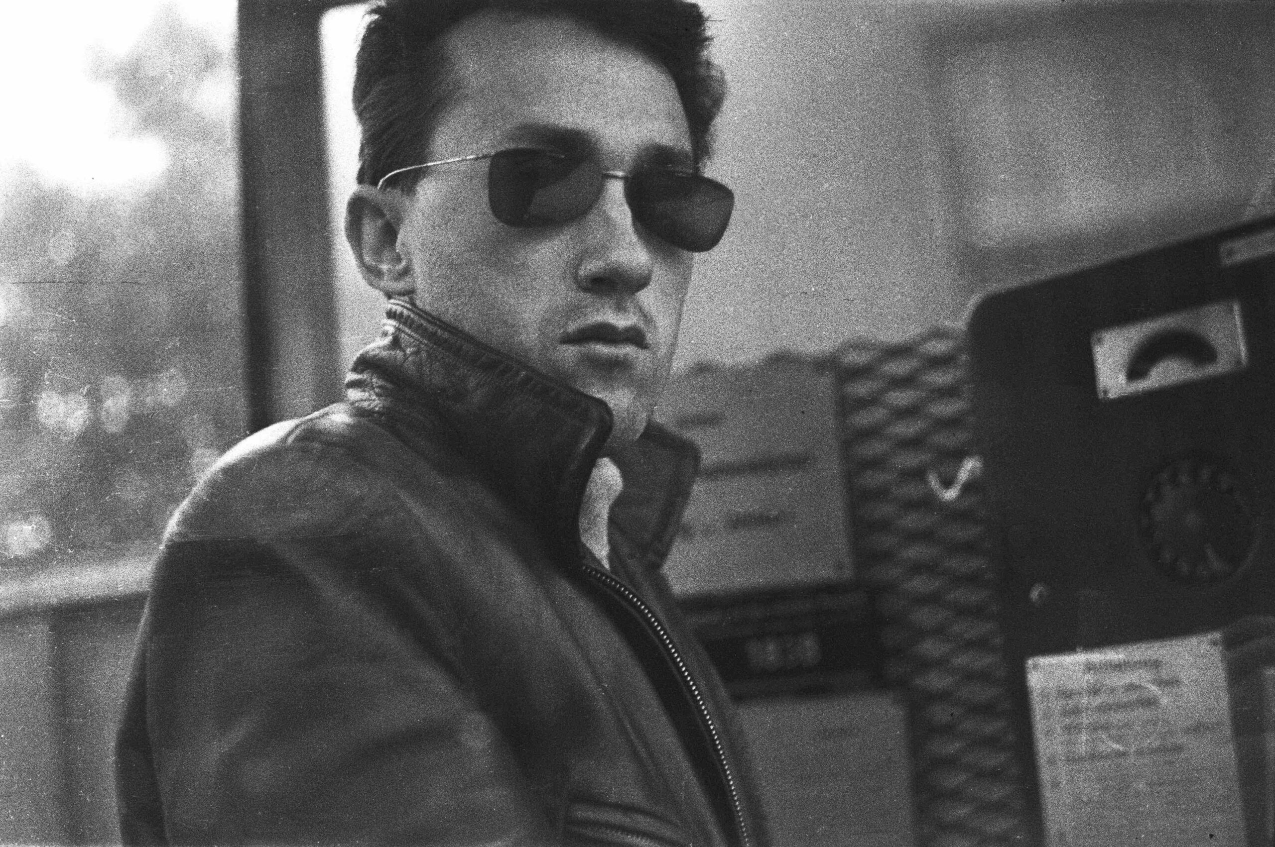 Schwarz-Weiß-Foto von Hans Scheugl in Sonnenbrille, lässig in Lederjacke posierend.