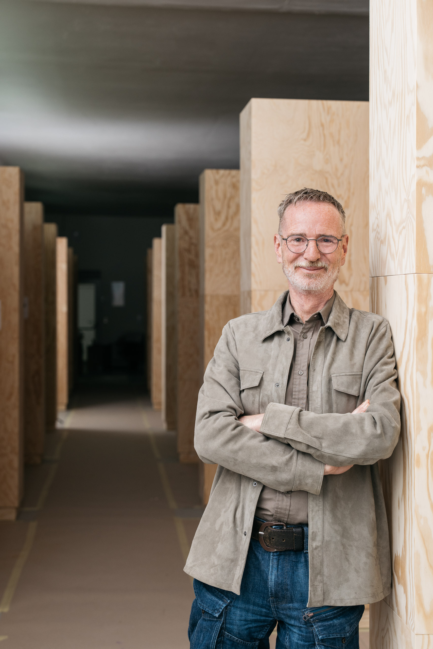 Hannes Sulzenbacher steht lächelnd in einem modernen, minimalistischen Raum mit Holzpaneelen.